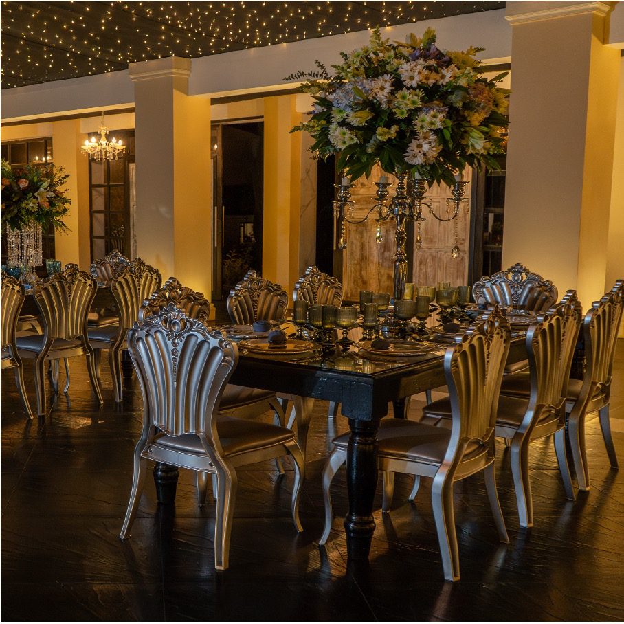 Mesa imperial con mobiliario de lujo, centro de mesa alto e iluminación wall washing en el salón de Amara Home, hacienda para bodas